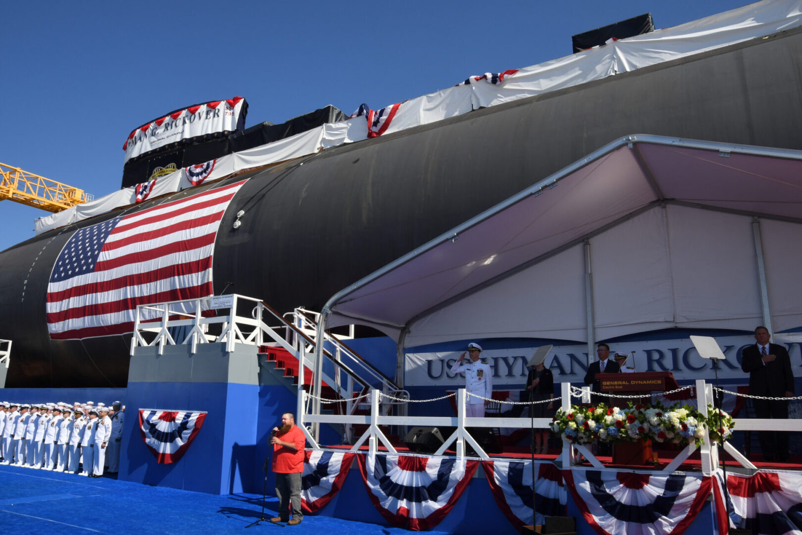 210731-N-GR655-043 GROTON, Conn. (July 31, 2021) – Scott Lacaillade, a shipyard employee, sings the national anthem in front of the pre-commissioning unit (PCU) Hyman G. Rickover (SSN 795) during a christening ceremony at General Dynamics Electric Boat shipyard facility in Groton, Conn., July 31, 2021. Rickover and crew will operate under Submarine Squadron (SUBRON) FOUR whose primary mission is to provide attack submarines that are ready, willing, and able to meet the unique challenges of undersea combat and deployed operations in unforgiving environments across the globe. (U.S. Navy photo by Chief Petty Officer Joshua Karsten/RELEASED)